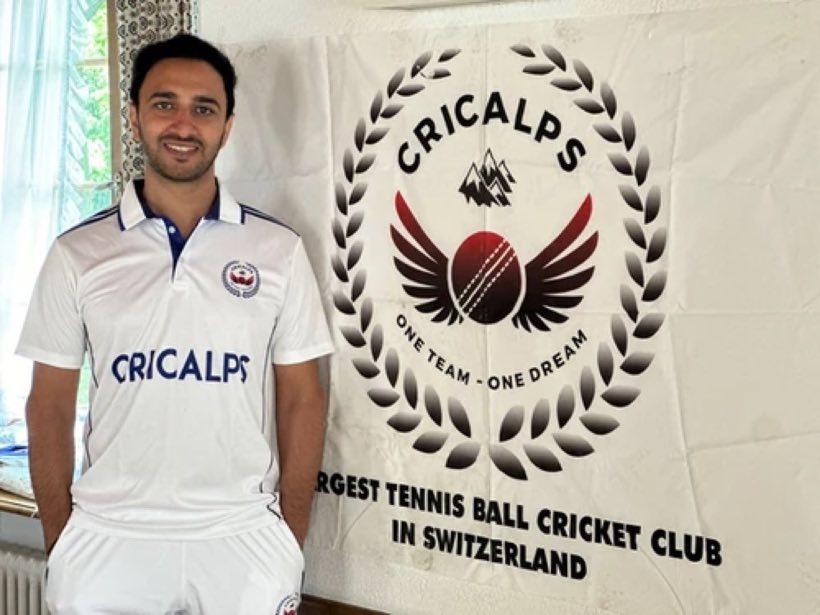 A young player in the white Cricalps shirt beside the club banner
