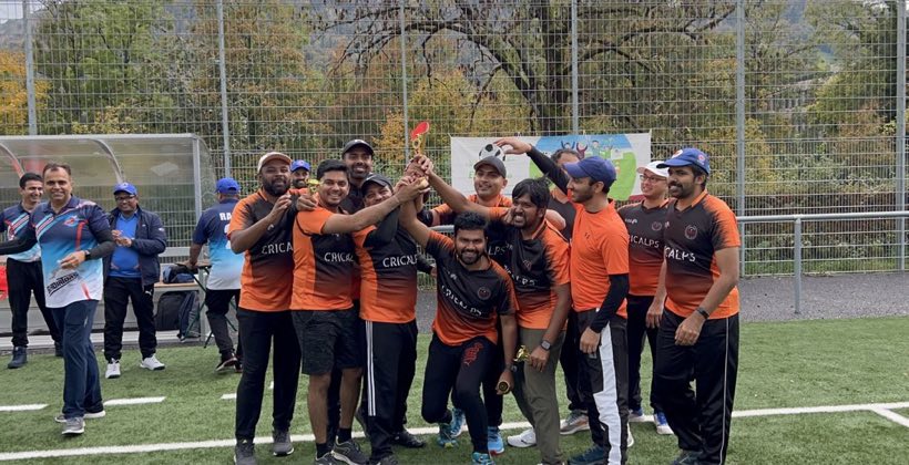 A team in orange kit crowded together celebrating, one arm raised