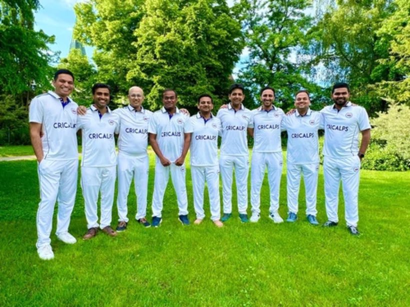 The team lined up in club whites on a lawn with trees behind